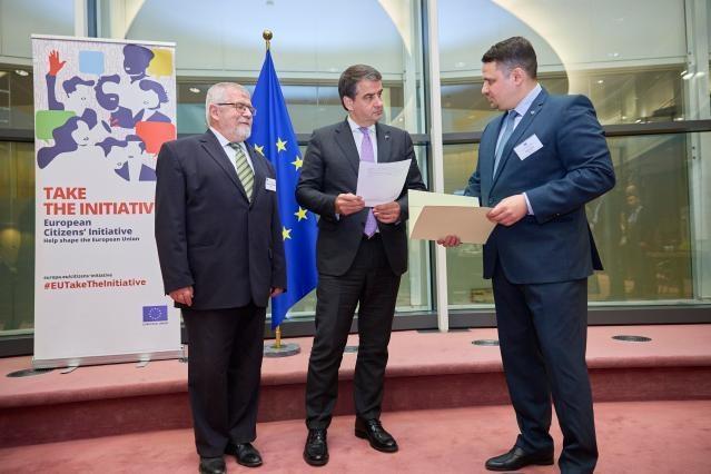 B.A. Izsak, Raffaele Fitto, A. Dabis, from left to right, against the backdrop of ECI banner with words "Take the Initiative'