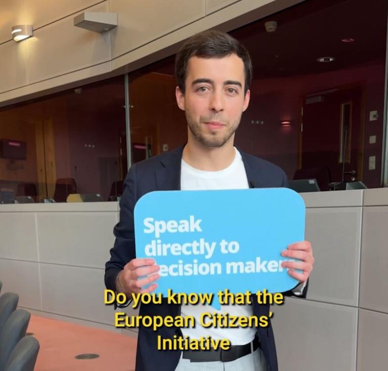 Young man holding a sign that reads 'Speak directly to decision makers'